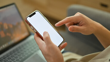 Man sitting on couch at home and using mobile phone. White empty screen for graphic display montage