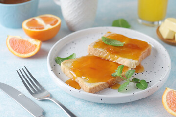 Sandwiches with marmalade, orange juice and coffee ready for breakfast