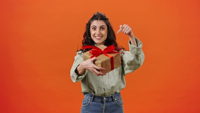Slow motion Caucasian brunette pretty woman catching a gift box, smiling and showing it at camera