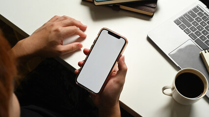 Above view of man sitting at white working desk and using smartphone. Blank screen for graphic display montage