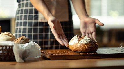 Male baker holding baked sourdough bread. Healthy eating and traditional bakery and pastry concept
