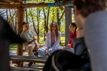 Happy young people sitting on wooden bench in the park