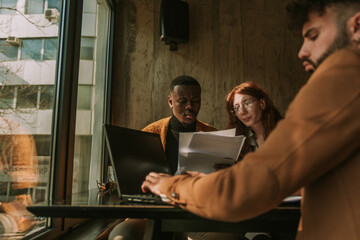 Low angle view of multiracial male and female colleagues discussing paperwork together while their...