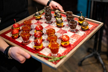 Drunken checkers. waiter hold checkers with shot alcoholic drinks and mini burgers