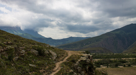 Dramatic landscape - the picturesque Baksan valley with a country road among the hills against the background of cloudy sky and foggy haze in the Elbrus region in the North Caucasus and copy space