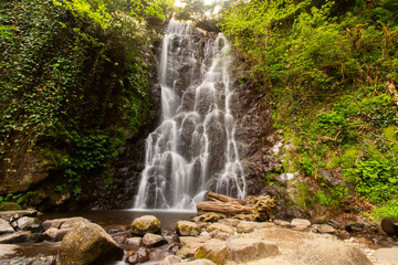 Obraz premium Remote waterfall with a wilderness feel and no signs of civilization, water stream falls from above from a rock onto stones