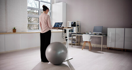 Fototapeta premium Woman Using Adjustable Height Standing Desk In Office