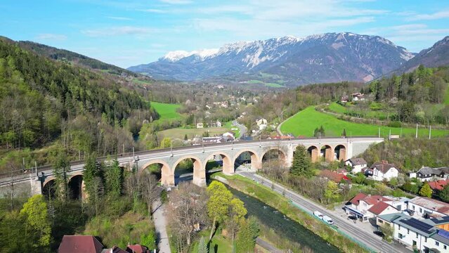 Railway viaduct of the historic Semmeringbahn in Austria with a passing OEBB Railjet train surrounded by beautiful mountain landscape