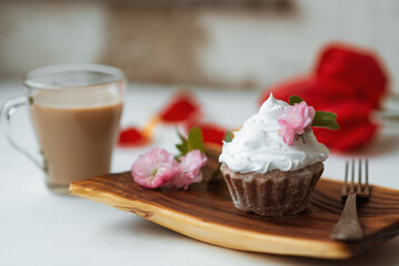 Cake and Coffee. Tasty cake with cream and pink flower decor in wooding plate. Red flowers on background