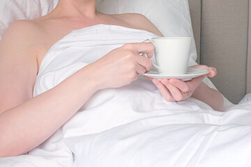 Woman drinks coffee in bed. Woman is resting in a hotel and relaxing