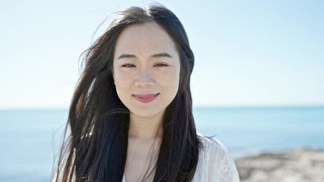 Young chinese woman smiling confident standing at seaside