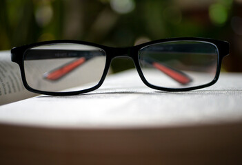 Black reading glasses on the islamic book with bokeh background, shallow focus