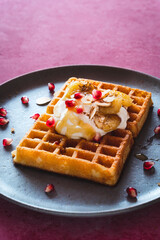 Waffel mit Joghurt Topping, karamellisierte Bananen, gerösteten Mandeln, Honig und Granatapfelkernen   