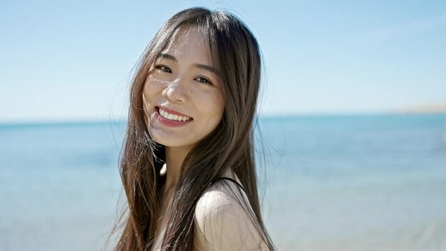 Young chinese woman tourist smiling confident wearing swimsuit at seaside