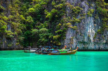 Naklejka na ściany i meble Many traditional longtail boats parking at Pileh Lagoon , Ko Phi Phi Leh island, part of Krabi, Thailand. View round with steep limestone hills and emerald green water.