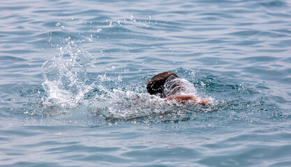 The boy swims in the waves of the sea