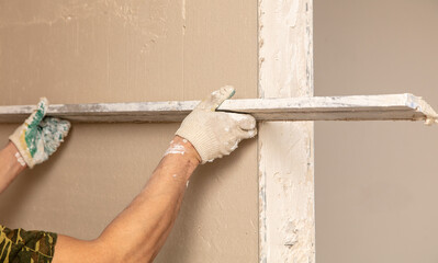 A worker is plastering the walls of a house under construction