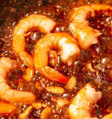 Shrimps are fried in oil in a frying pan