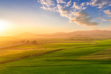 Obraz premium scenery rural view of a contryside farm in green fields and hills with amazing cloudy sky on background