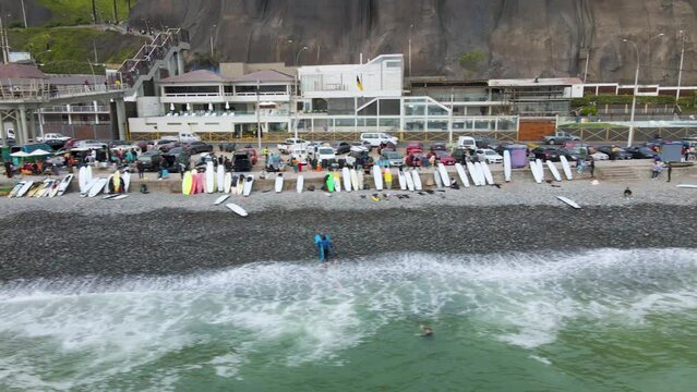 4K Aerial Drone Horizontal Tack along Rocky Beach with Surfers, Boards, and traffic in Lima, Peru