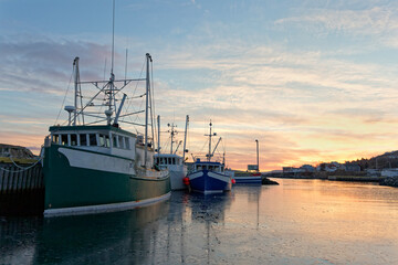Fishing boats moored at the dock at sunset during the winter, Port de Grave, Newfoundland and...