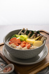 Vegetables soup with chicken ball and egg tofu in gray bowl on concrete table.