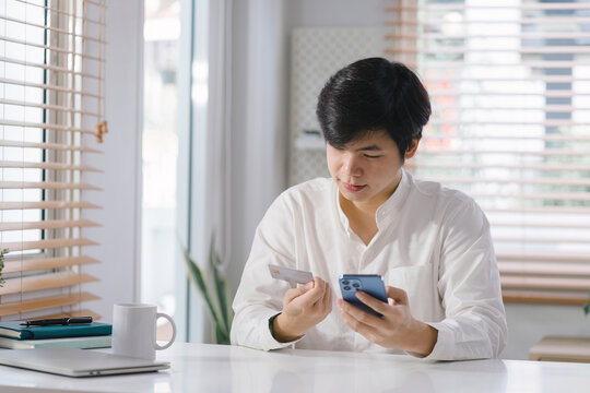 Cropped Shot Of Millennial Man Is Paying With A Credit Card Online While Placing Orders Via Mobile Internet And Making Transactions Using A Mobile Banking Application.