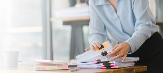 Cropped shot of businesswoman is sifting through stacks of paper files and folders that contain...
