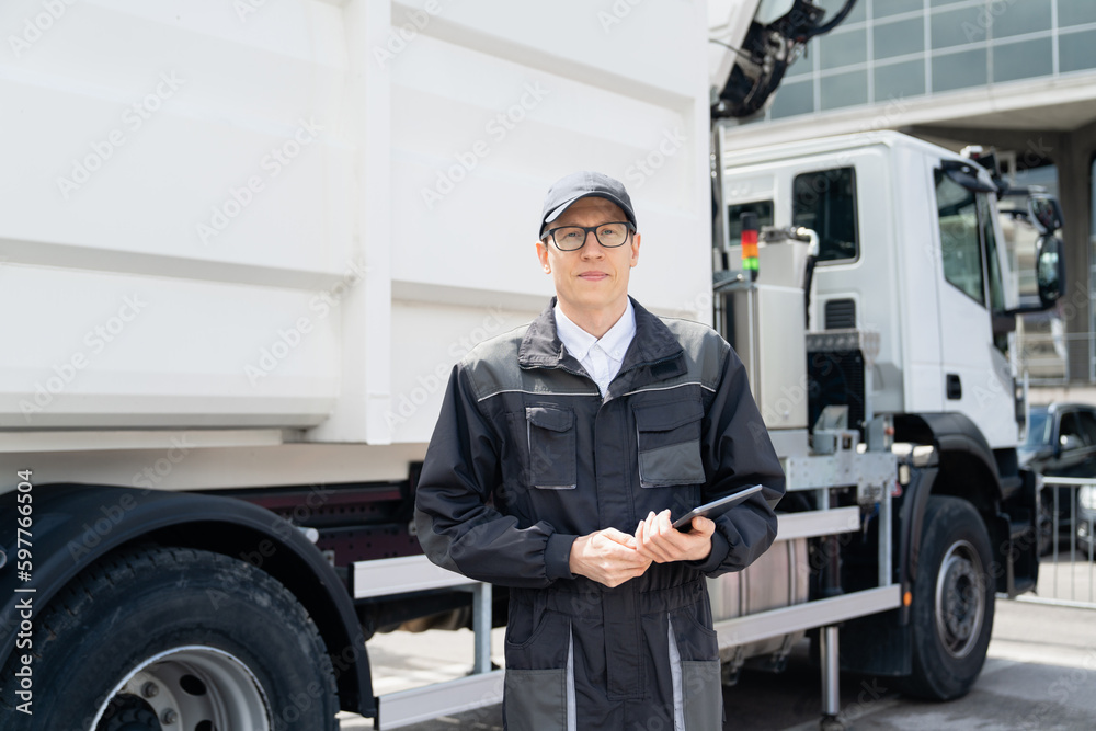 Poster manager with a digital tablet next to garbage truck.