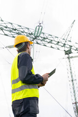 Engineer with digital tablet on a background of power line tower	