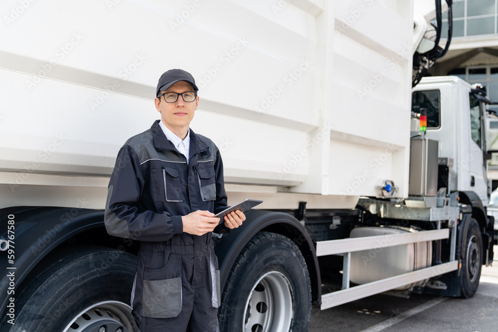 Poster manager with a digital tablet next to garbage truck.