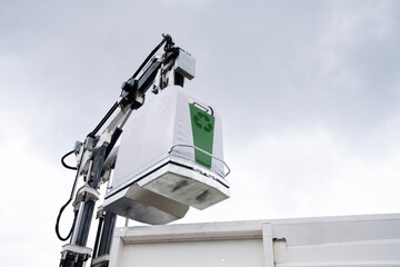 Garbage truck lifts street bin for recyclable waste