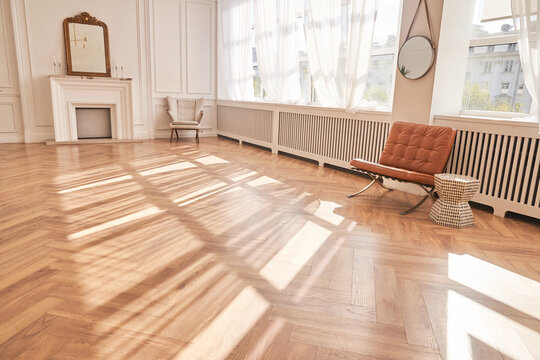 Bright interior with large windows and a fireplace in a classic style. Large living room with decor items. Beautiful parquet and copy space. Sunlight and shadows in the room. High quality photo