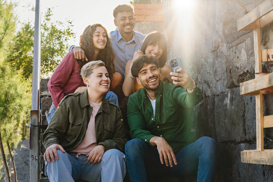 Seafront Steps Selfie: Young multiethnic friends taking a group selfie on seafront steps, enjoying their time together.