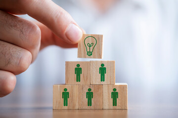 Man holding a wooden cube with light bulb on it. Teamwork and employment business concept