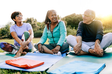Happy senior people after yoga sport class having fun sitting outdoors in park city - Elderly fitness concept