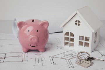 Piggy bank with drawings and model of house. Building and design of new house concept