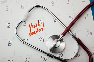 Doctor appointment reminder note on calendar with stethoscope close-up