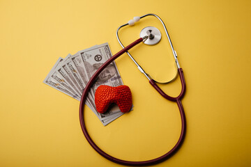 Model of thyroid gland, dollar banknotes and stethoscope on a yellow background. Health care insurance or savings