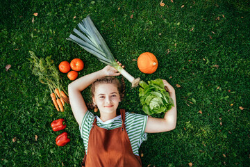 Above view portrait of teenager girl with different vegetables eco food on the grass.
