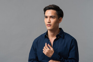 Studio portrait of young handsome Asian man wearing dark blue shirt looking away in light gray isolated background - Powered by Adobe