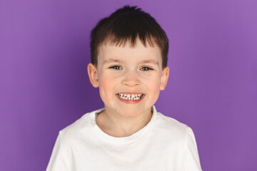 Portrait of happy joyful laughing beautiful little boy wear white t-shirt, look at camera, smiling isolated on purple violet background.