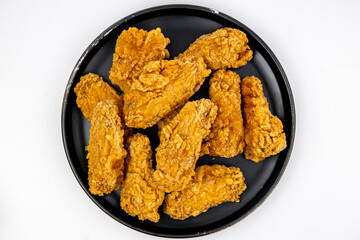 Fried chicken wings on a black plate isolated on white, top view