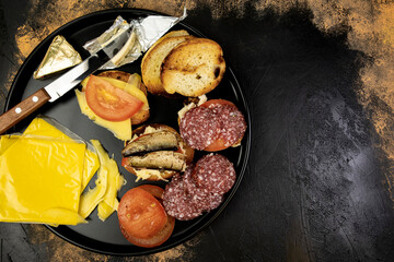 Round plate with sandwiches with fish, sausage and cheese on the meat table, top view