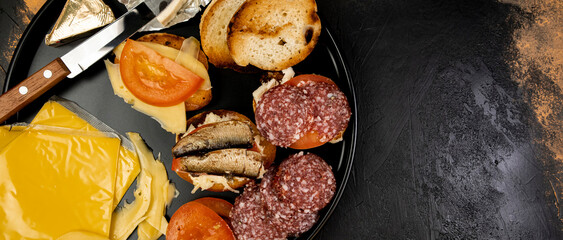 Wide view, round plate with sandwiches with fish, sausage and cheese on the meat table, top view