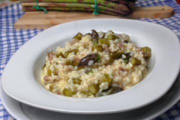 Dish with risotto of green asparagus and pieces of sausage.