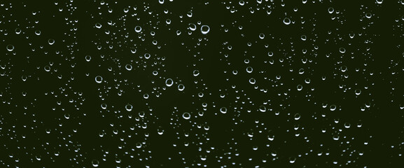 Fototapeta na wymiar Atmospheric minimal monochrome backdrop with rain droplets on glass. Wet window with rainy drops and dirt spots closeup. Blurry minimalist background of dirty window glass with raindrops close up.