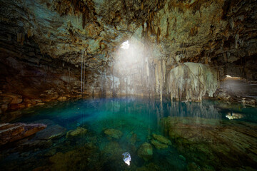 Fototapeta na wymiar Cenote Dzitnup Xkeken, cave south of Valladolid. Landscape in Yucatán, Mexico. Green blue water lake in cave, light in the hole. Travel in Mexico.
