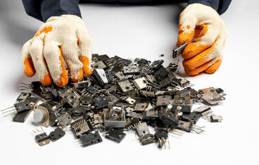 Close up of man hands wearing gloves with ICs, transistors, diodes isolated on white background....