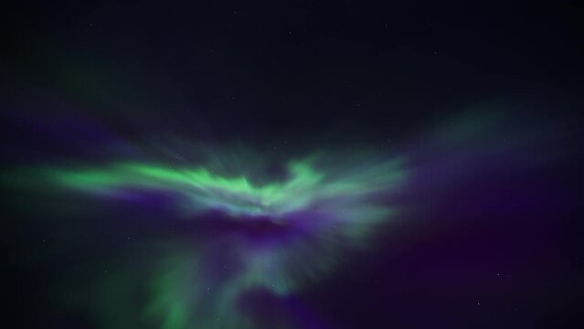 Colorful Northern Lights (Aurora Borealis) appear overhead on the night sky. Timelapse. 